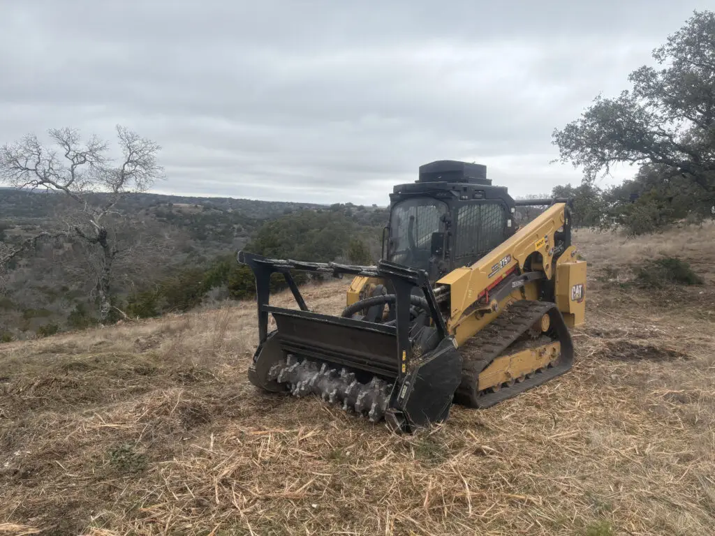Hilliland Contracting CAT compact track loader with drum forestry mulching head on a Texas Hill Country hilltop clearing brush near Seguin, TX